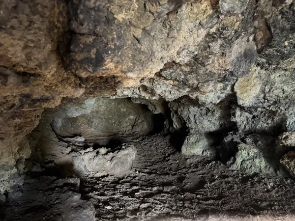 Der Blick in eine dunkle Höhle mit unebenem, erdigem Boden und zerklüfteten Felswänden am Staffelberg. Die raue Gesteinsoberfläche zeigt natürliche Vorsprünge und eine dunkle Öffnung im Hintergrund.